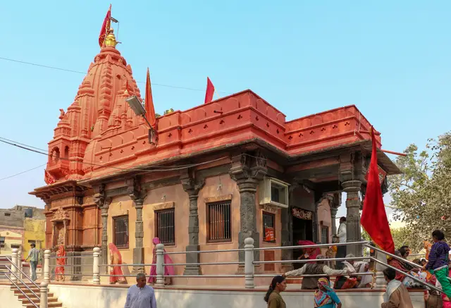 शिखर और स्तंभों वाले मंडप के साथ हरसिद्धि माता का लाल रंग का मंदिर